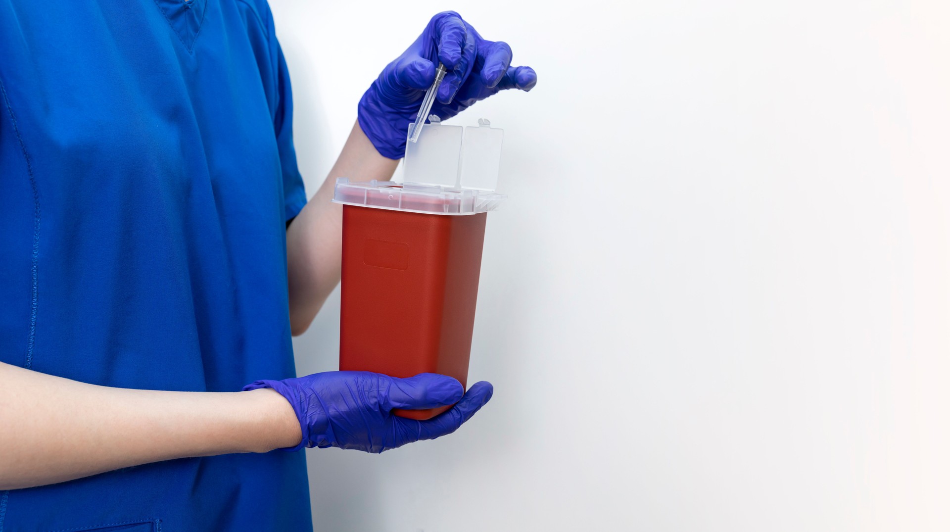 Mockup Doctor Disposes Needle, Ampule In Sharps Container. Disposal Container For Infectious Waste, Reducing Medical Waste Disposal. Small Medical Plastic Box With Sharps For Bio Hazard. Copy Space.
